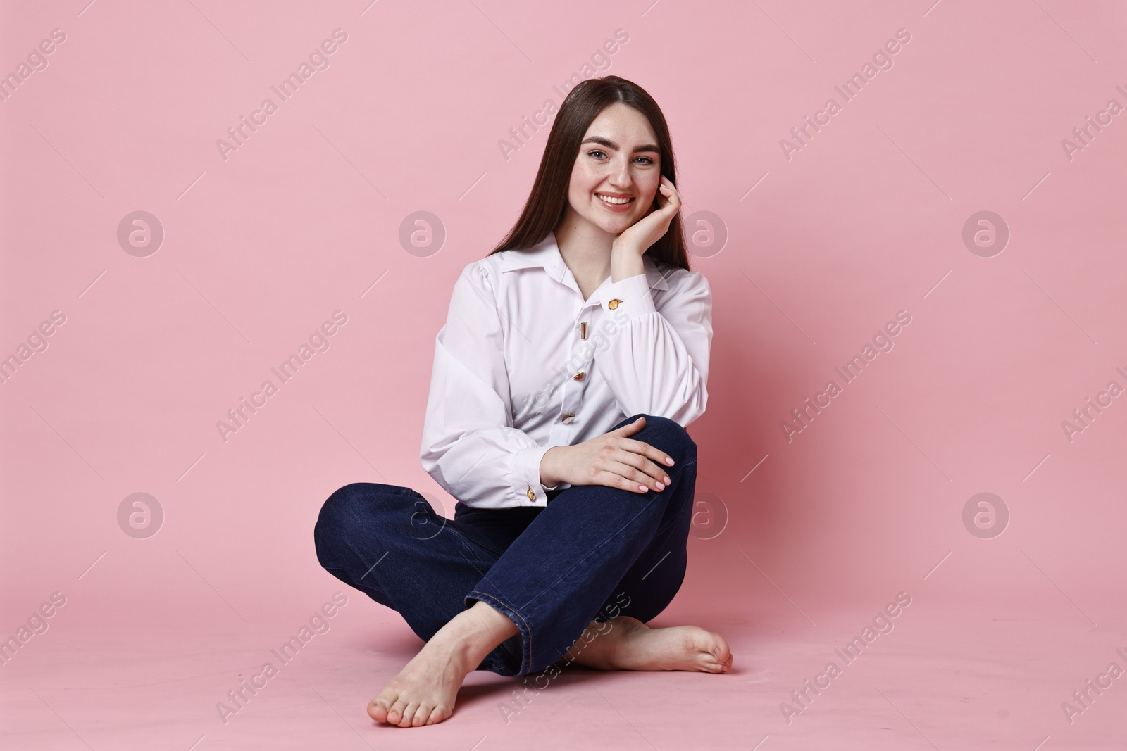 Photo of Smiling woman in stylish jeans on pink background