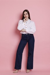 Photo of Beautiful young woman in stylish jeans on pink background