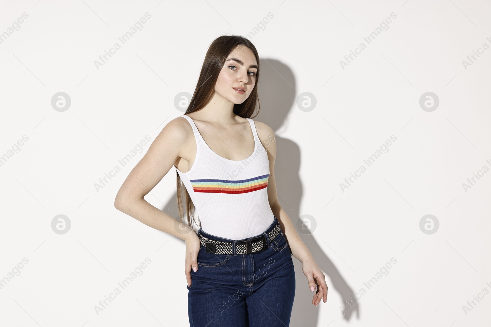 Photo of Beautiful young woman in stylish jeans on light background