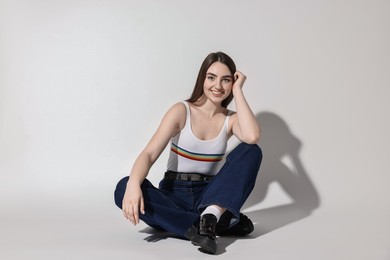 Photo of Smiling woman in stylish jeans on light grey background