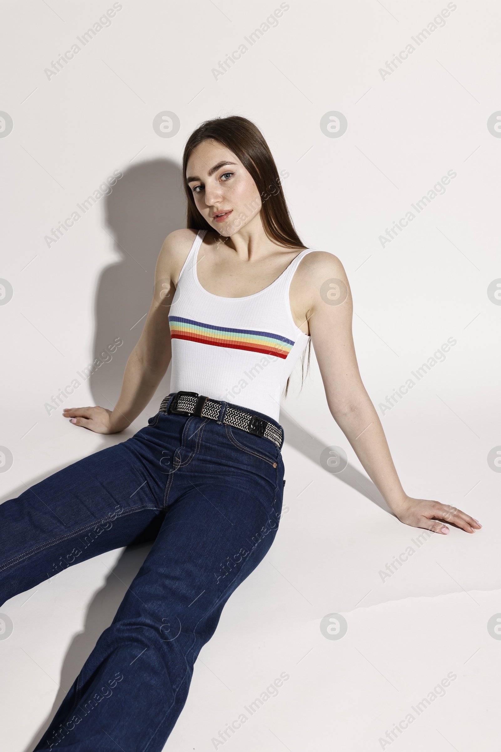 Photo of Beautiful young woman in stylish jeans posing on light background