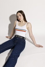 Photo of Beautiful young woman in stylish jeans posing on light background