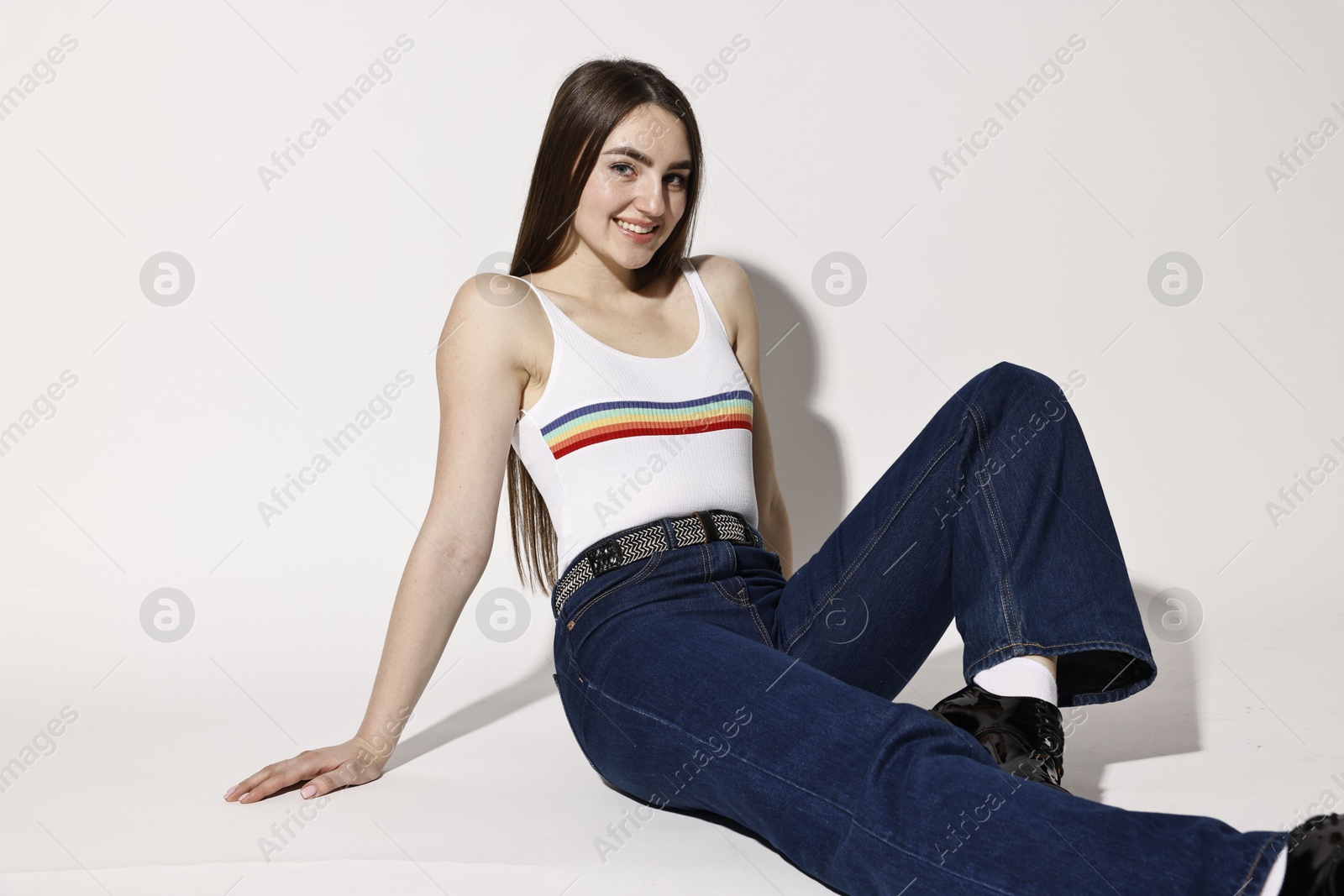 Photo of Happy woman in stylish jeans posing on light background