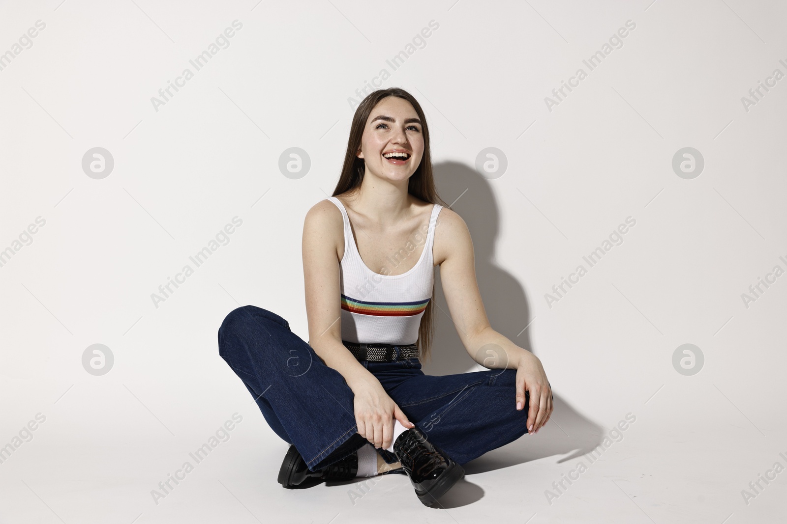 Photo of Happy woman in stylish jeans posing on light background