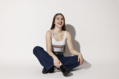 Photo of Happy woman in stylish jeans posing on light background