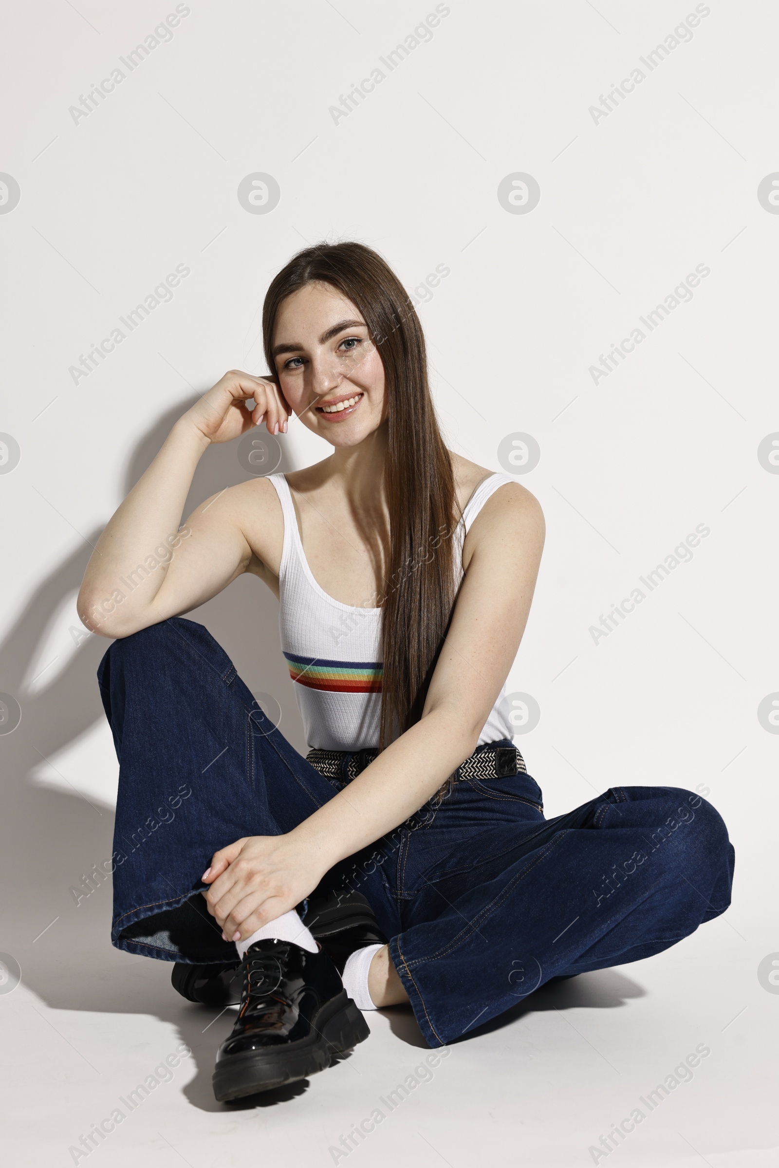 Photo of Smiling woman in stylish jeans on light background