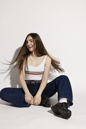 Photo of Happy woman in stylish jeans on light grey background