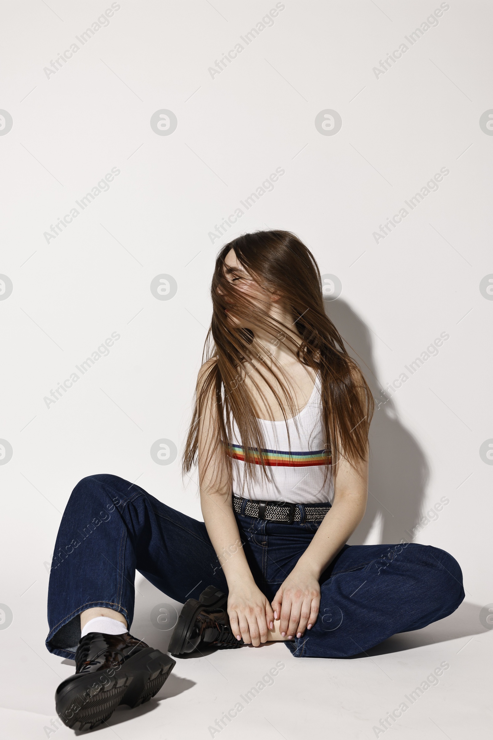 Photo of Woman in stylish jeans on light grey background