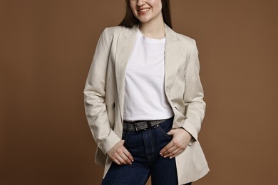 Photo of Smiling woman in stylish jeans on brown background, closeup