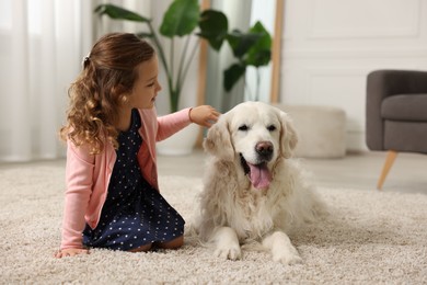 Photo of Little girl with cute dog on carpet at home