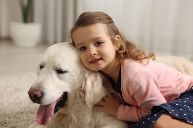 Photo of Little girl with cute dog on carpet at home