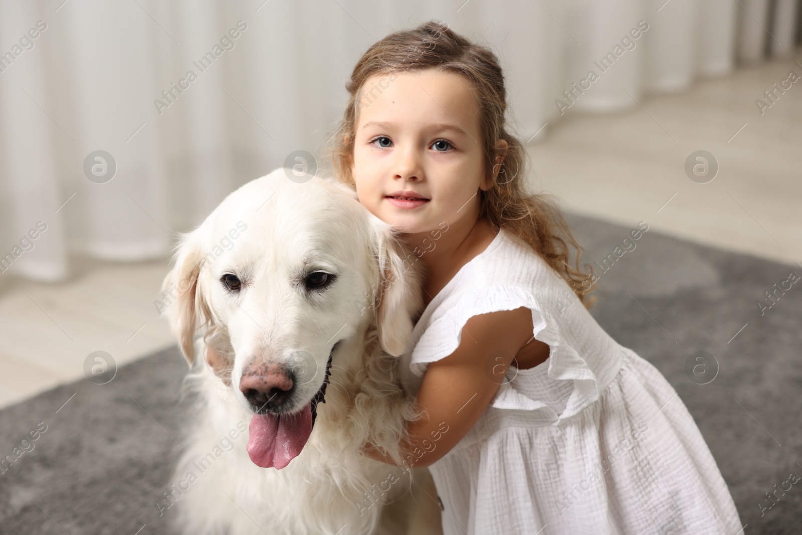 Photo of Little girl with cute dog on carpet at home