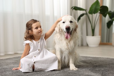 Photo of Little girl with cute dog on carpet at home