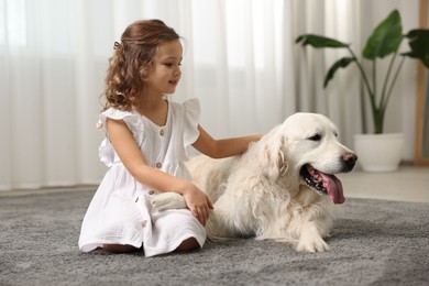 Photo of Little girl with cute dog on carpet at home