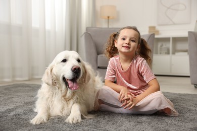 Photo of Little girl with cute dog on carpet at home