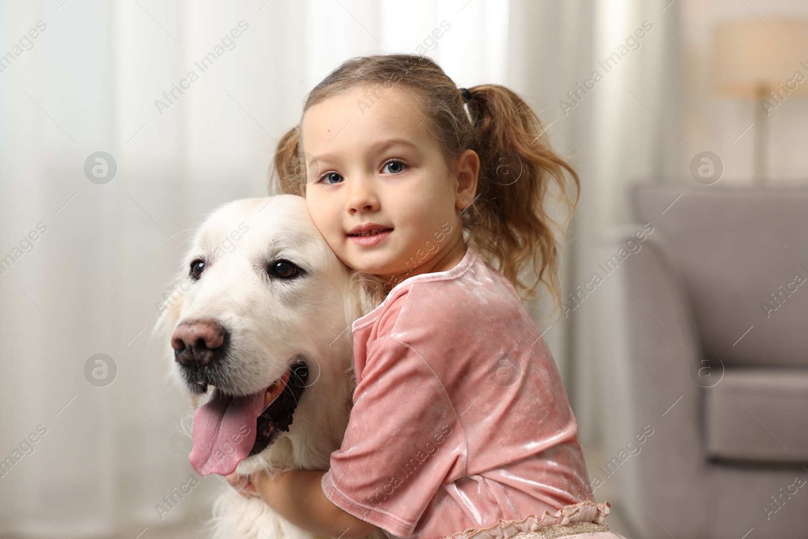 Photo of Little girl with cute dog at home