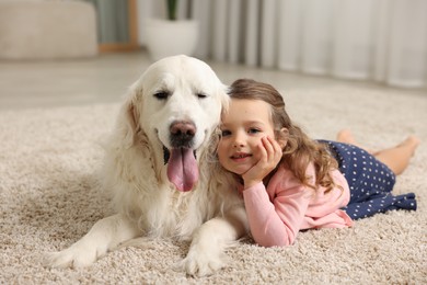 Photo of Little girl with cute dog on carpet at home