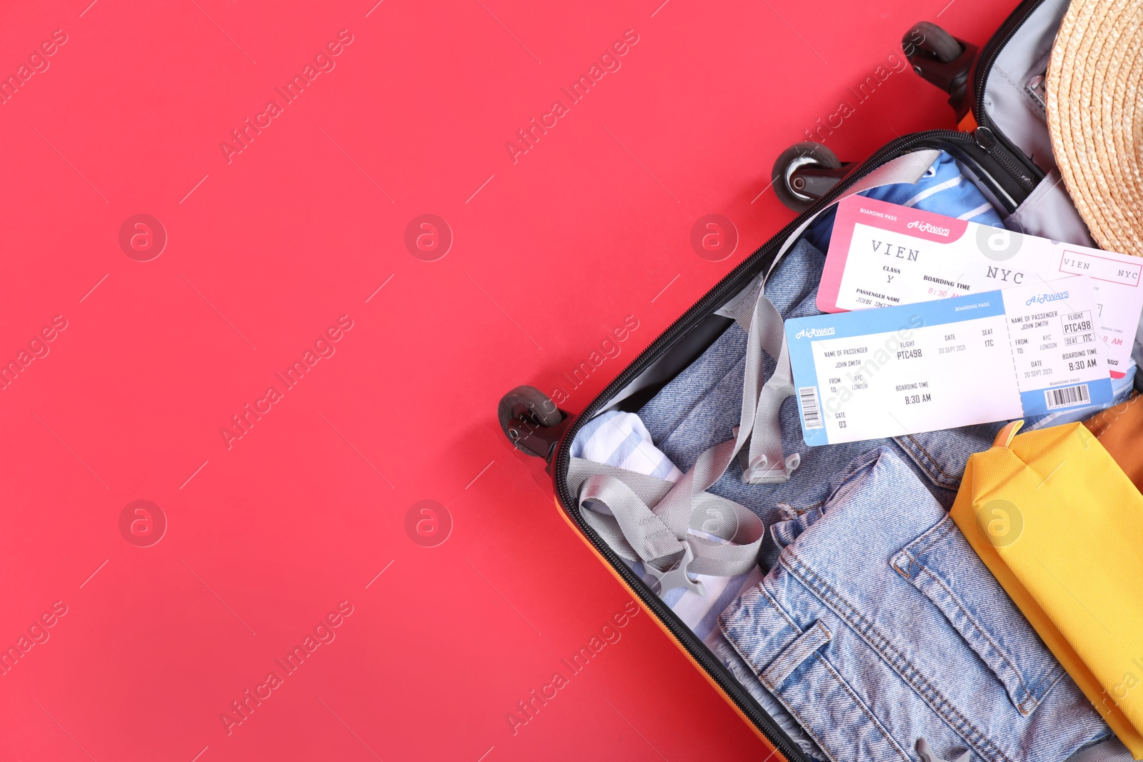 Photo of Travel abroad. Packed suitcase with tickets on red background, top view. Space for text