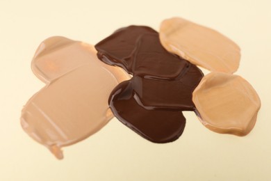 Photo of Samples of different foundations on beige background, closeup