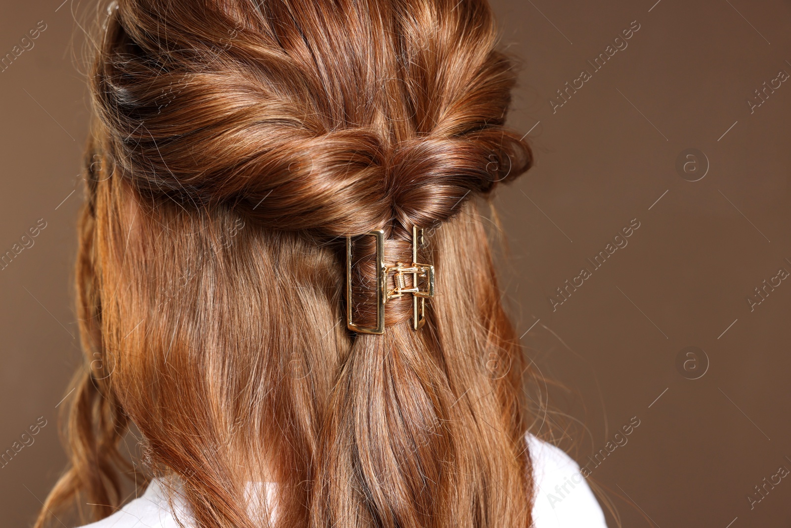 Photo of Teenage girl with stylish hair clip on brown background, back view