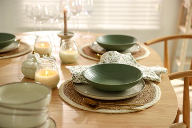 Photo of Stylish table setting with dishware, cutlery and burning candles indoors