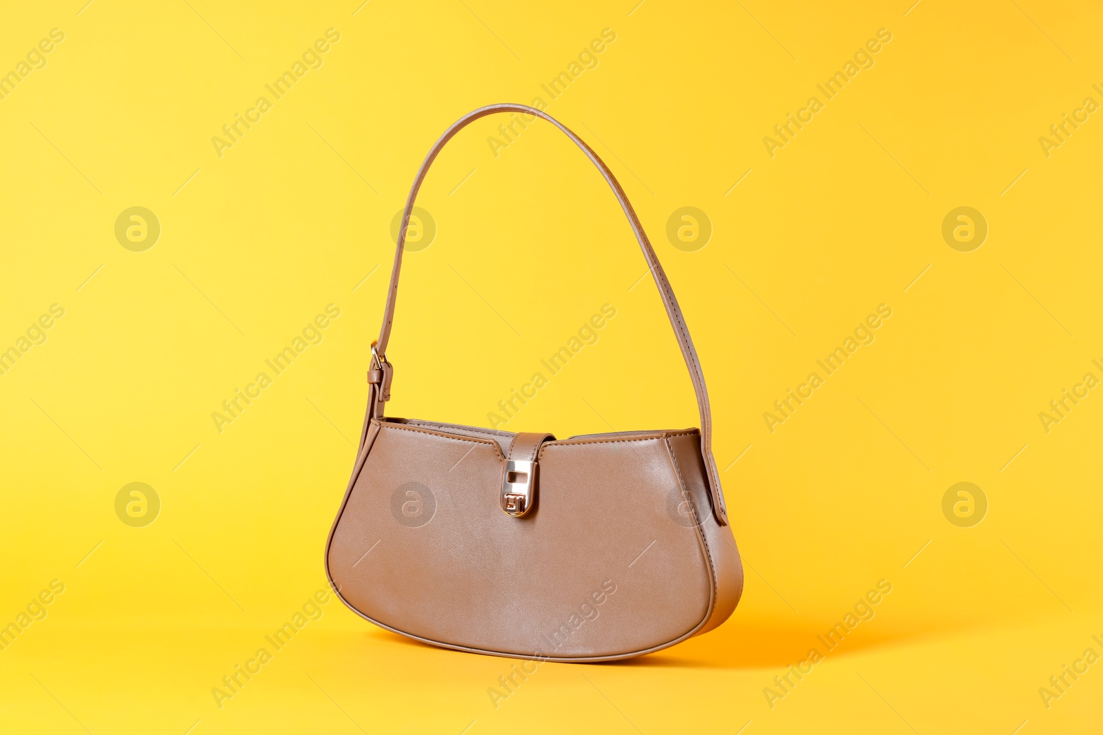 Photo of Stylish brown leather bag on yellow background