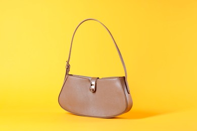 Photo of Stylish brown leather bag on yellow background