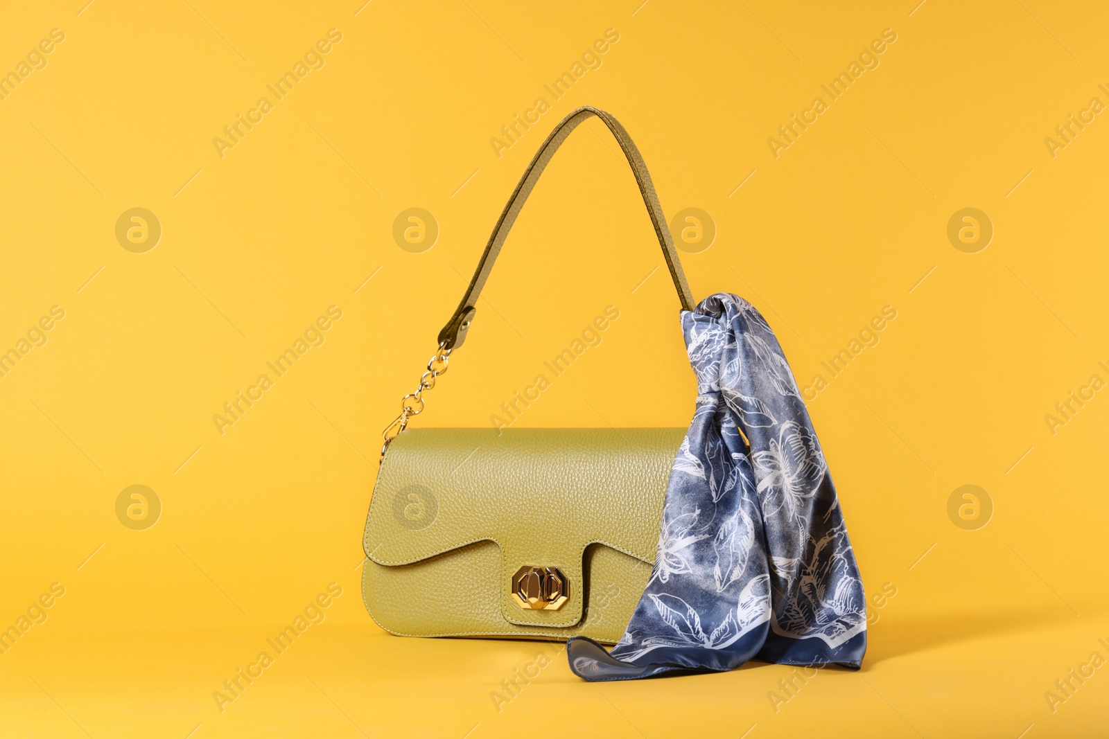 Photo of Stylish leather bag with handkerchief on yellow background