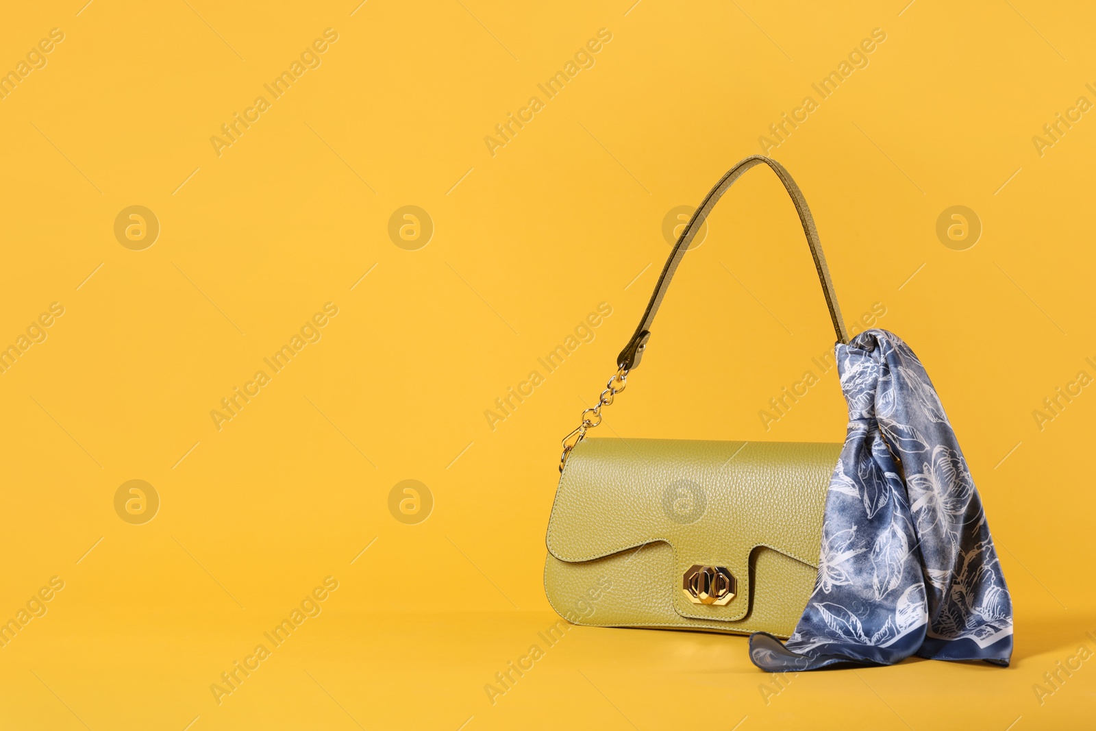 Photo of Stylish leather bag with handkerchief on yellow background, space for text