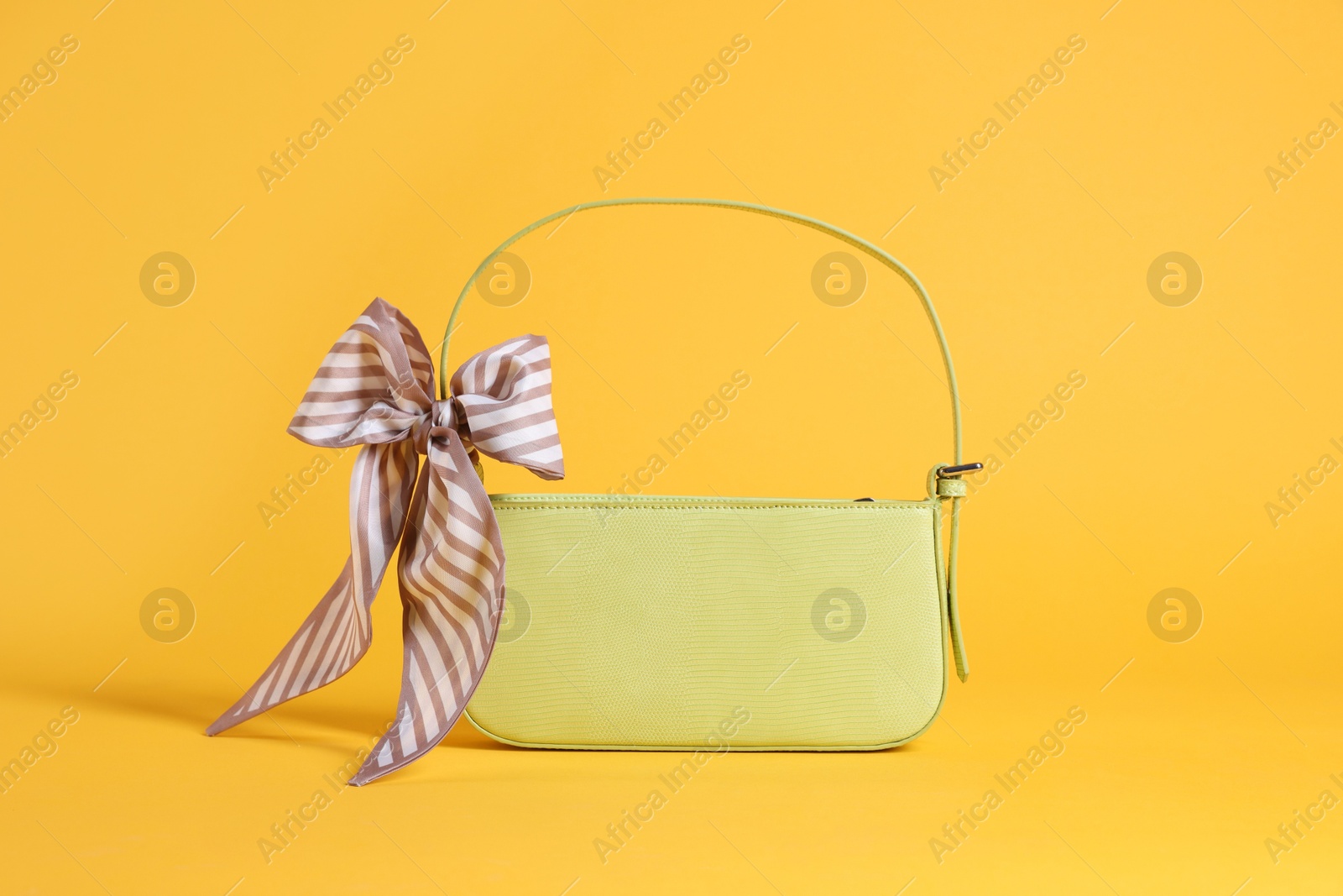 Photo of Stylish light green leather bag with handkerchief on yellow background