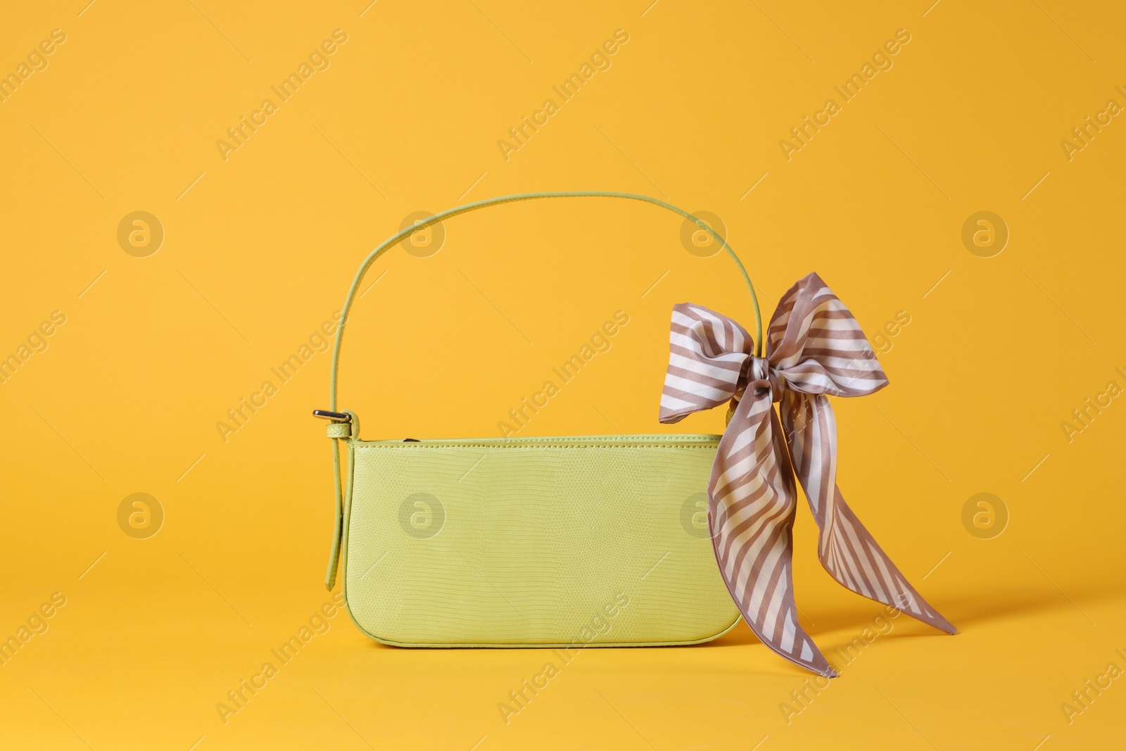 Photo of Stylish light green leather bag with handkerchief on yellow background