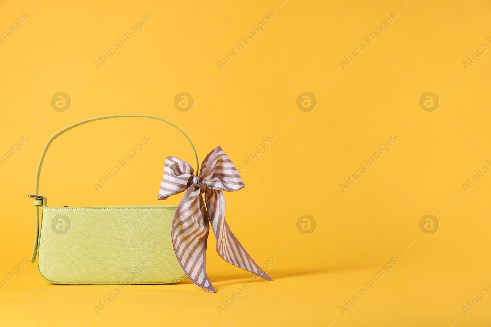 Photo of Stylish light green leather bag with handkerchief on yellow background, space for text