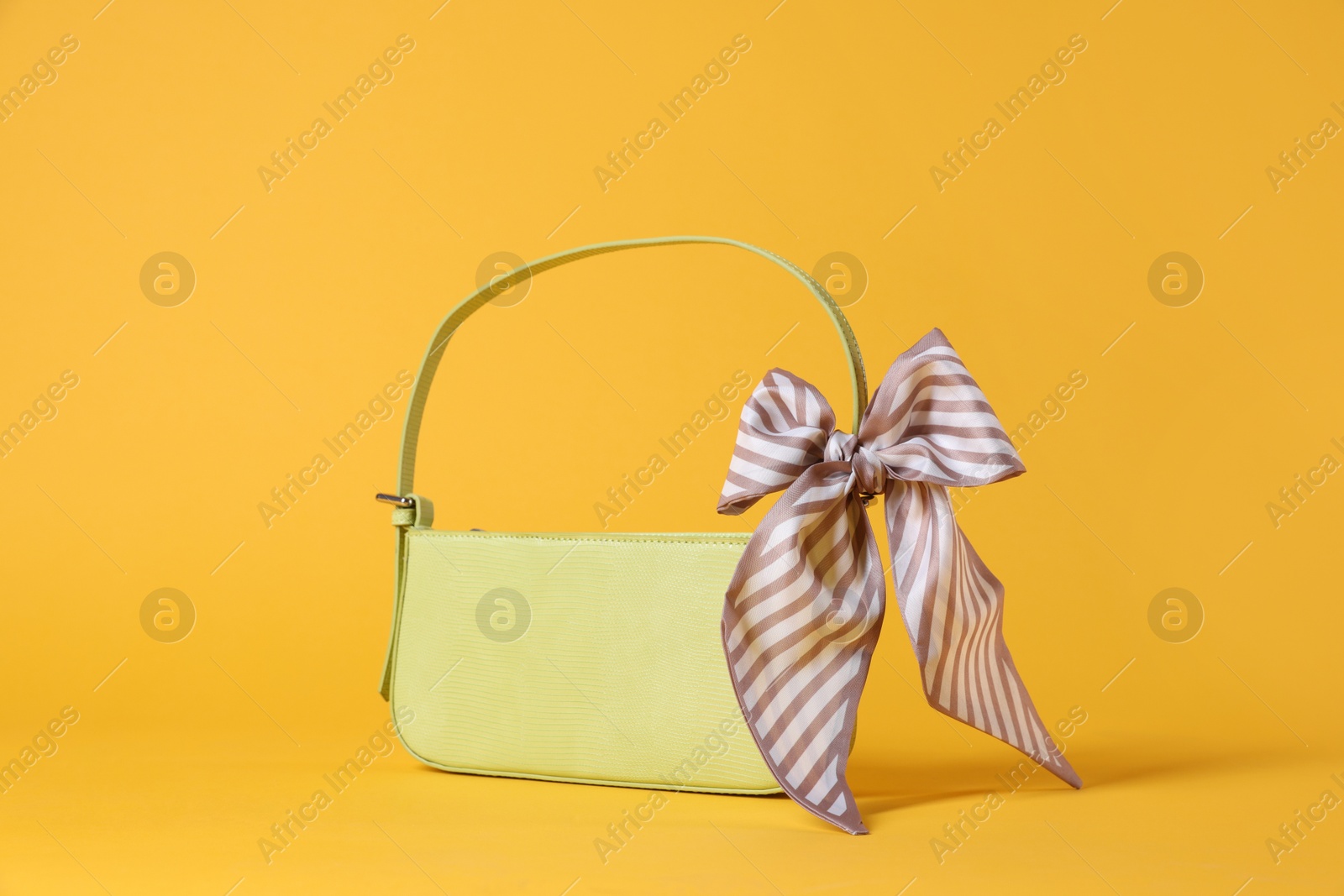 Photo of Stylish light green leather bag with handkerchief on yellow background,