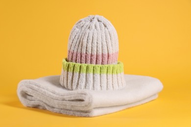 Photo of Stylish knitted hat and warm scarf on yellow background