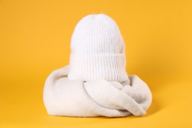 Photo of Stylish knitted hat and warm scarf on yellow background