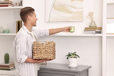 Photo of Male decorator arranging decor onto shelf at home