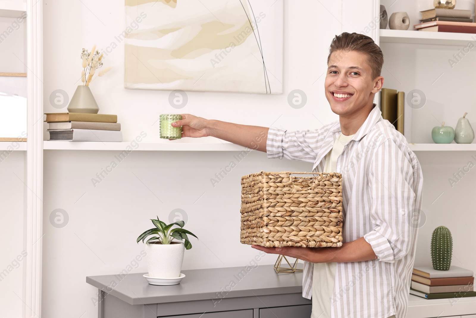 Photo of Smiling decorator arranging decor onto shelf at home