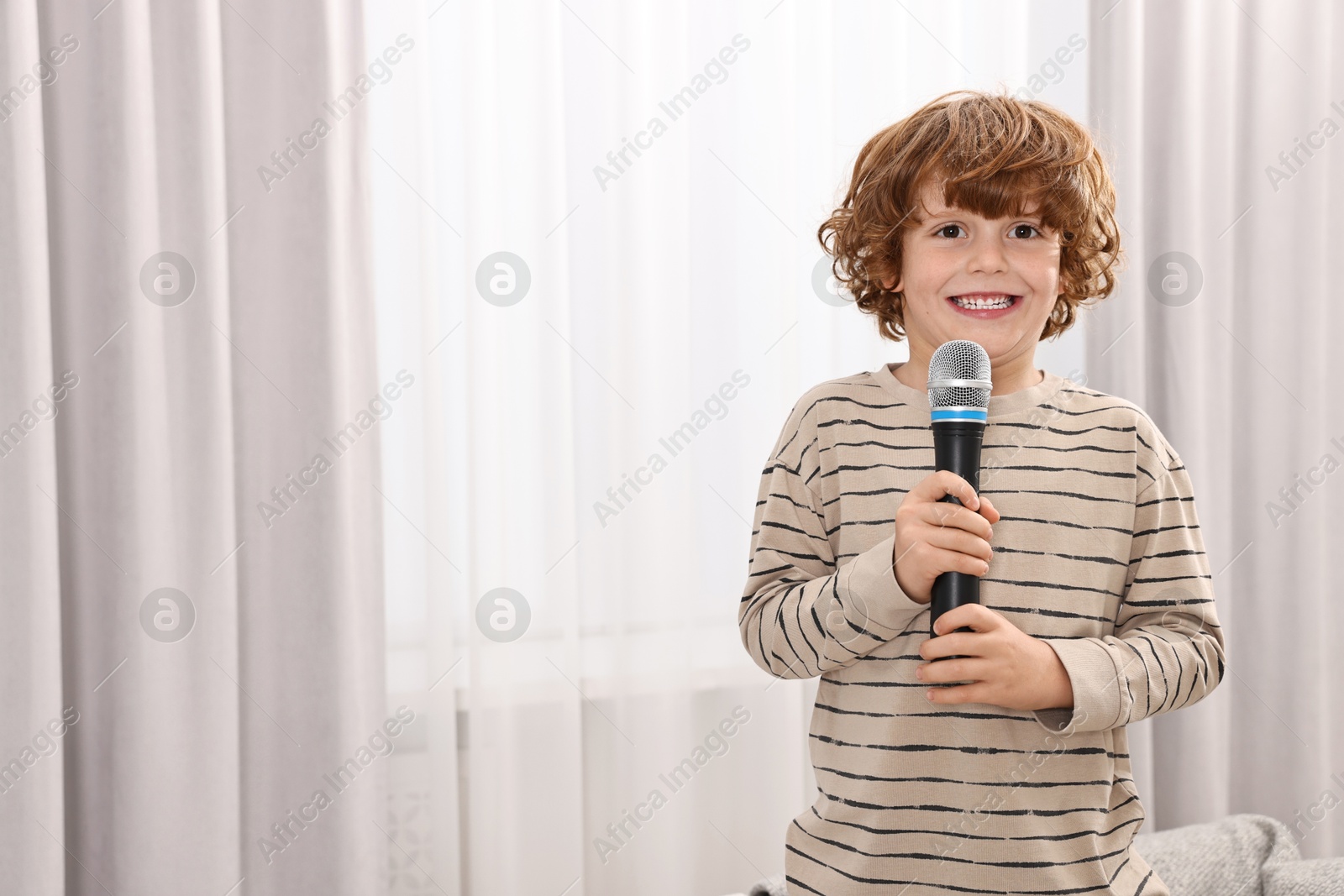 Photo of Little boy with microphone on sofa at home