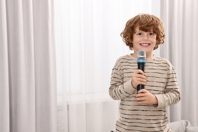 Photo of Little boy with microphone on sofa at home