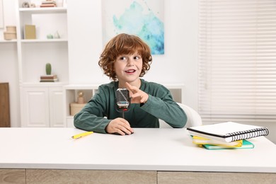 Photo of Little boy with microphone at white table indoors