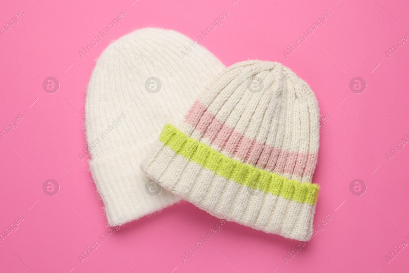 Photo of Warm woolen hats on pink background, top view