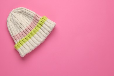 Photo of Warm woolen hat on pink background, top view. Space for text