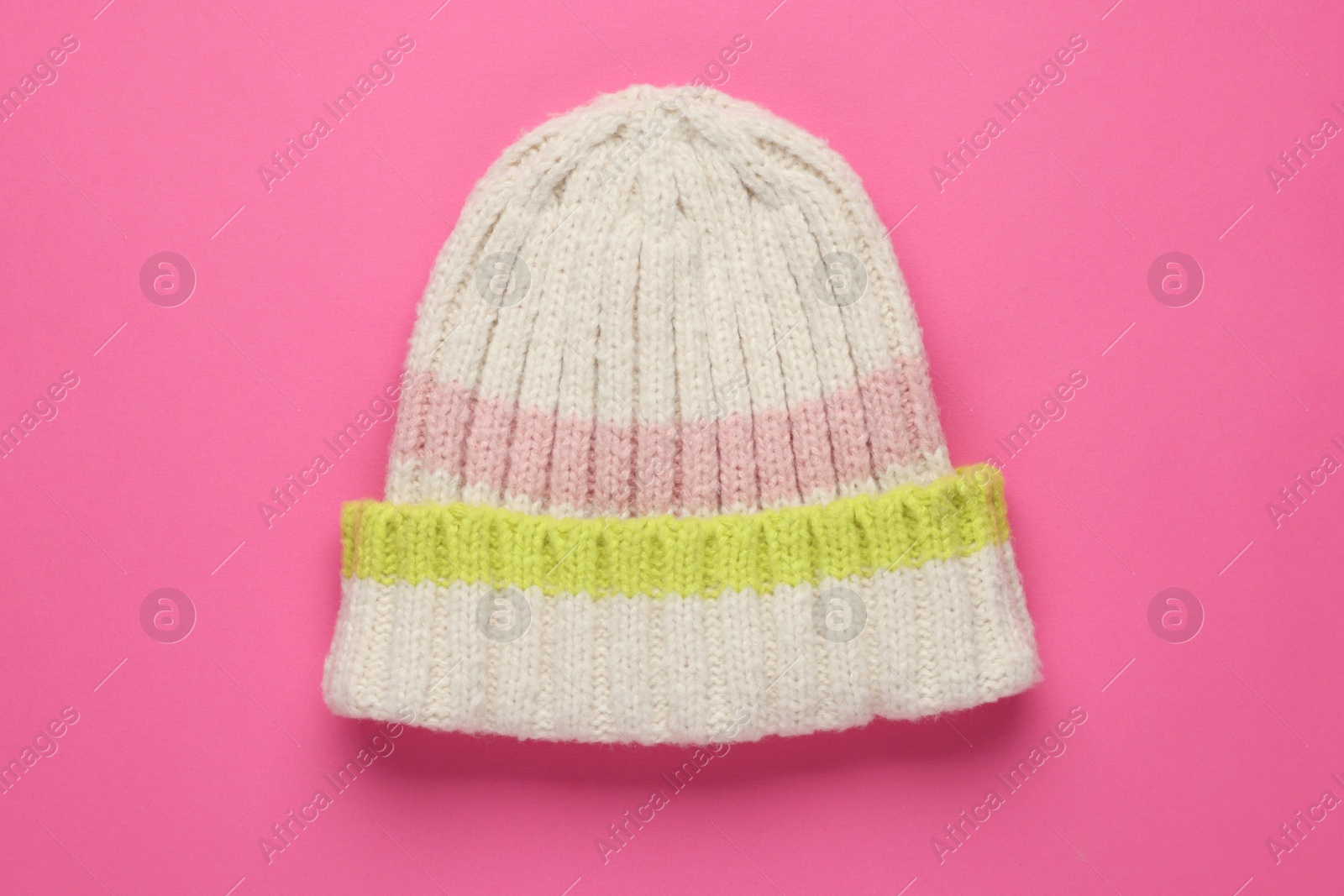 Photo of Warm woolen hat on pink background, top view