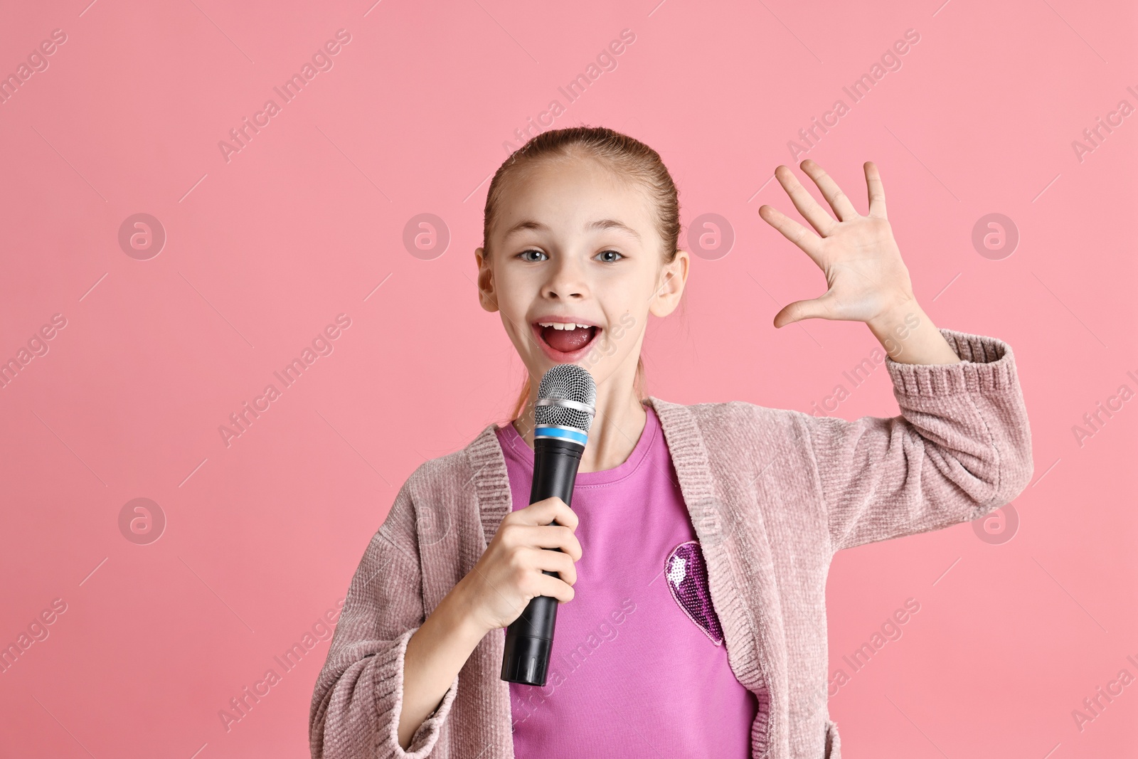 Photo of Little girl with microphone singing on pink background