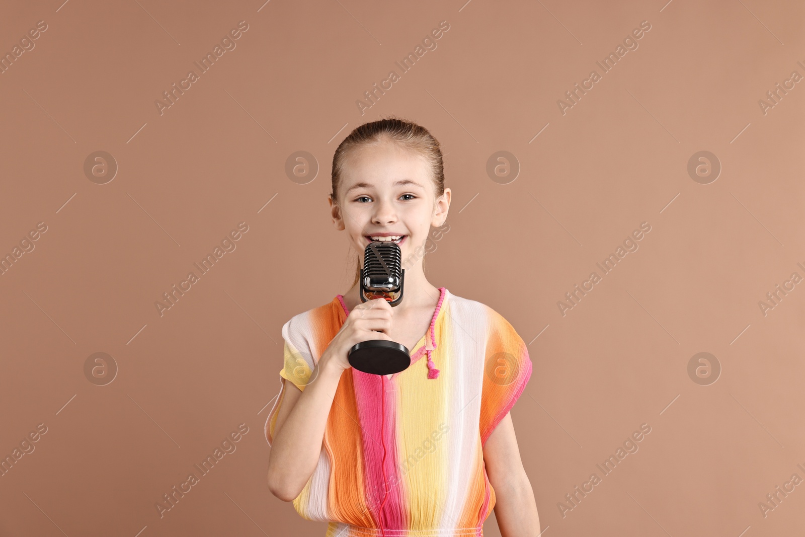 Photo of Little girl with microphone on light brown background