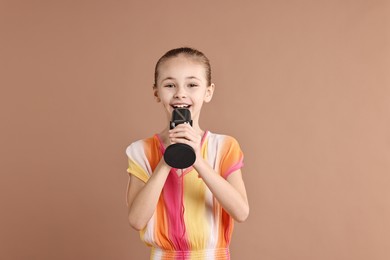 Photo of Little girl with microphone on light brown background