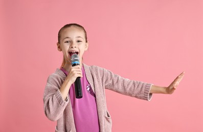 Photo of Little girl with microphone singing on pink background