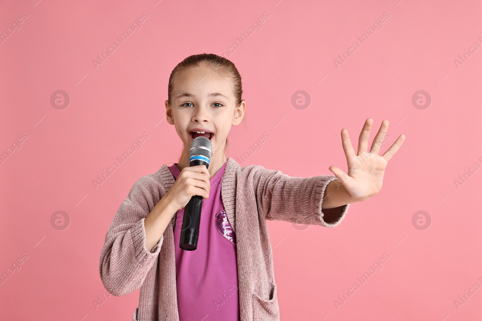 Photo of Little girl with microphone singing on pink background