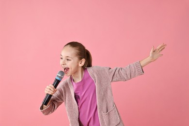 Photo of Little girl with microphone singing on pink background