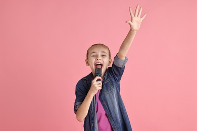 Photo of Little girl with microphone singing on pink background